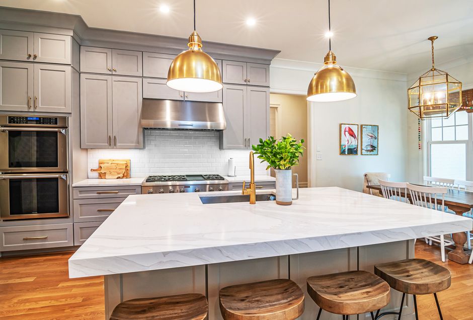 A professionally staged, bright modern kitchen with a clean marble island, showcasing a home prepared for sale to maximize its market value.
