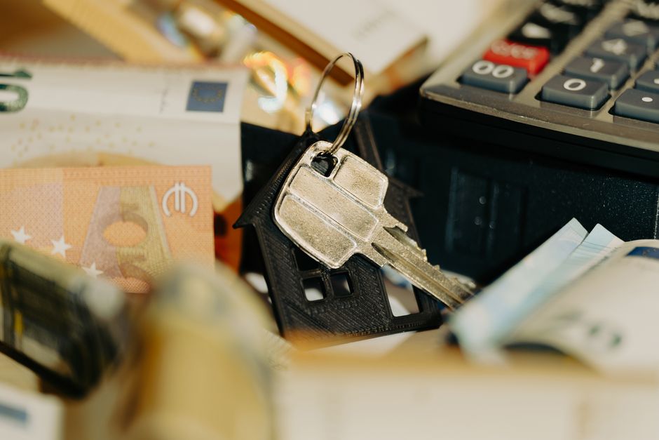 A clean, professional desk scene with a calculator next to a set of house keys, symbolizing the financial calculations of real estate commissions.