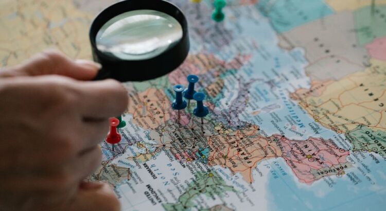 Professional person stands looking at a large wall map with various locations, symbolizing strategic analysis of different...