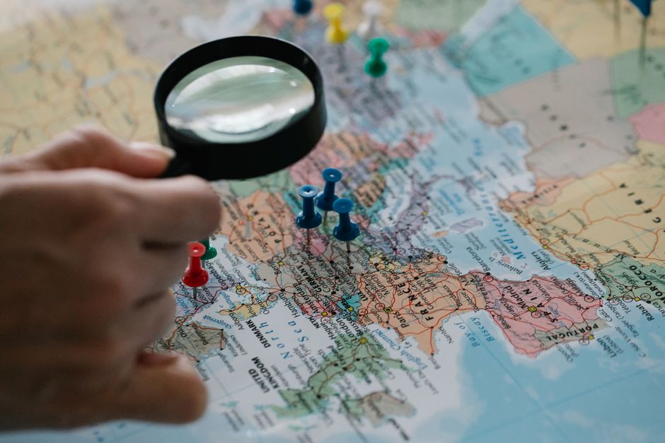 Professional person stands looking at a large wall map with various locations, symbolizing strategic analysis of different...
